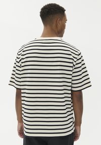 Akiniai trumpomis rankovėmis, dryžuoti, kreminės ir juodos spalvų, laisvo kirpimo, pagaminti iš medvilnės, su apvaliu kaklu ir tiesiais kraštais.