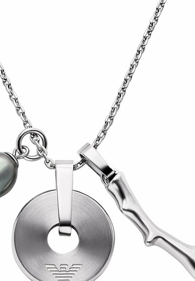 Collier chaîne en argent avec un pendentif rond orné d'un logo gravé, un petit charm en forme d'os en argent, et un accent de perle noire.