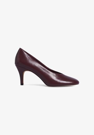 Chaussure à talon haut en cuir bordeaux avec un bout pointu, au design épuré et d'une hauteur de 7 cm. Elle présente une texture lisse et aucune décoration visible.