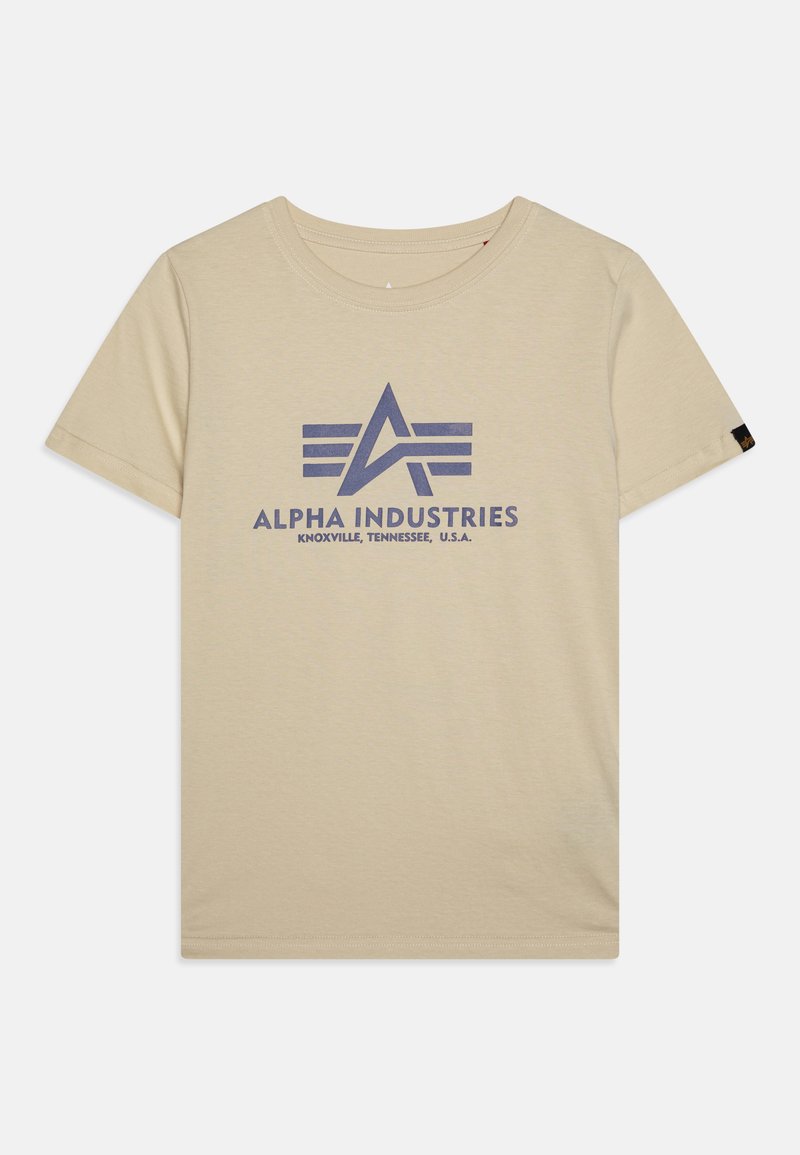 Beige bomullströja med korta ärmar, med en stor blå tryck av "ALPHA INDUSTRIES"-loggan och stiliserad design på framsidan.