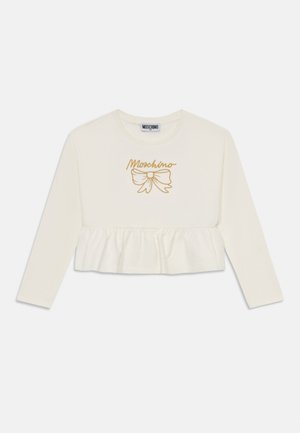 Biela dlhá blúzka s volánovým lemom. Na prednej strane sa nachádza vyšívaný zlatý nápis "Moschino" a motív mašle. Hladký bavlnený materiál.