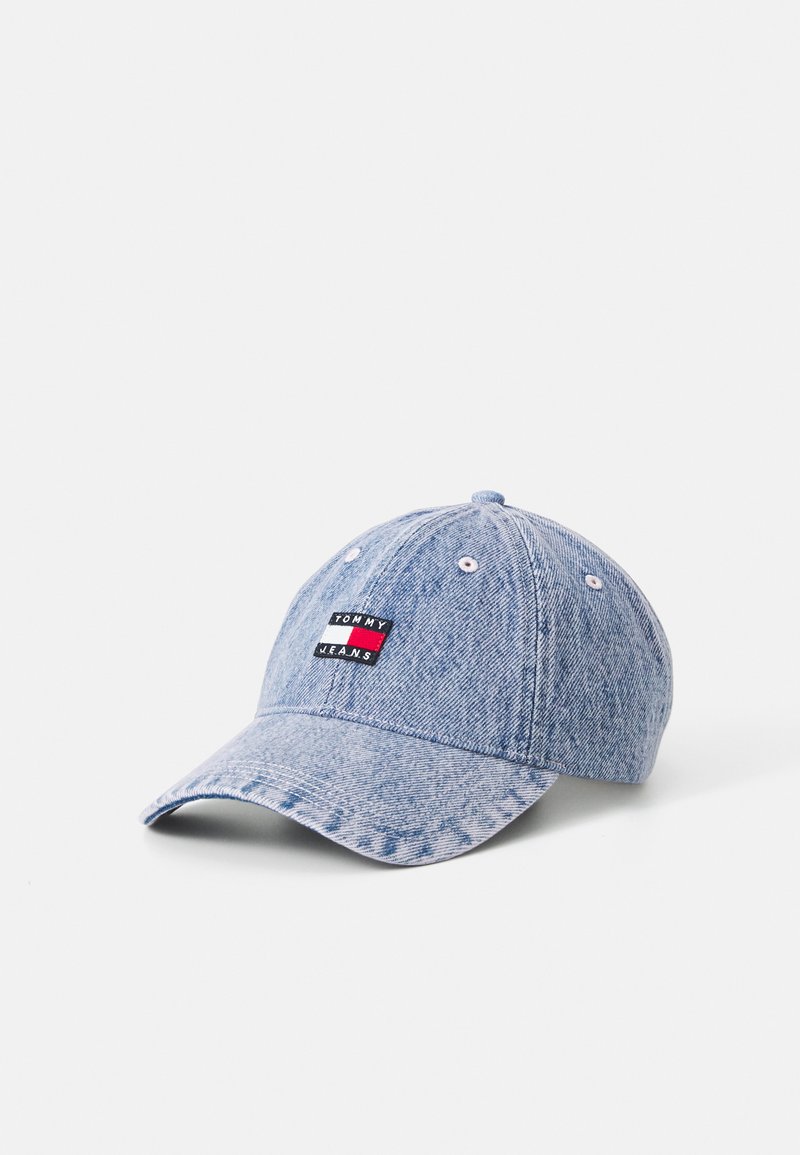 Denim blauwe baseballcap met een gebogen rand, voorzien van een gestikt logopatch in rood, wit en zwart aan de voorkant. Geweven stof.