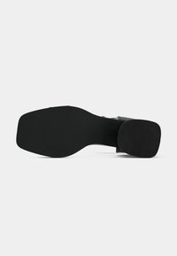 Schwarze Schuhsohle mit glatter Oberfläche und abgerundeter Zehenpartie. Verfügt über einen leichten Absatz und ein strukturiertes Muster für besseren Halt.