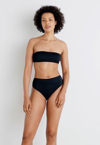 Ensemble de bikini noir comprenant un haut bandeau sans bretelles et un bas taille haute, fabriqué en tissu lisse et extensible avec une finition texturée.