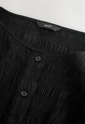 Czarna koszula o fakturowanym, marszczonym wzorze, z zapięciem na guziki i metką marki "NEXT" w pobliżu dekoltu.