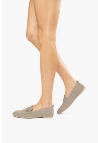 Beige Slipper mit einer glatten Wildleder-Oberfläche, die mit einem dekorativen Metallelement und einer niedrigen, beigen Gummisohle versehen sind.