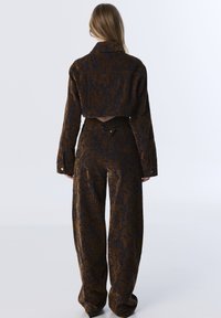 Brown and dark blue patterned cropped jacket with long sleeves and wide-leg pants, featuring button details and a textured fabric.