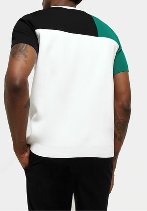 Kurzarmshirt mit Farbblocks in Schwarz, Weiß und Grün, strukturiertem Stoff und geripptem Kragen. Taillierte Passform mit seitlichem Saum.