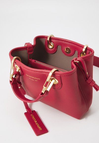 Bolso de mano de cuero rojo con una superficie texturada, acentos en dorado, y una correa ajustable. Cuenta con un interior espacioso y etiqueta de la marca.