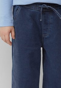 Donkerblauwe denim broek met een elastische tailleband, trekkoord en zijzakken, met een gladde textuur en een klassieke recht-pijp ontwerp.