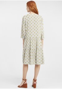 Rochie cu imprimeu floral, până la genunchi, cu mâneci până la trei sferturi, design în straturi, în nuanțe de galben și alb, și guler rotund.