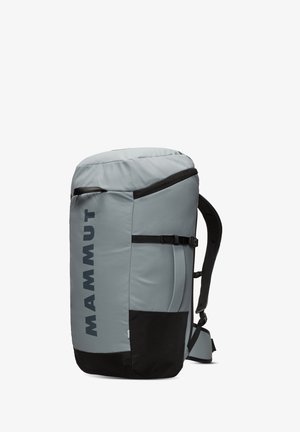Sac à dos Mammut gris avec un haut arrondi, des bretelles réglables, une fermeture éclair latérale, une section inférieure noire et un grand logo de la marque sur le côté.
