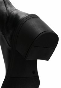 Black ankle boot with a chunky heel, smooth leather texture, rounded toe, and visible stitching accents along the sides.