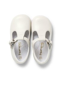Zapatos de cuero blanco con punta redonda, tira ajustable y plantilla perforada. Presentan un cierre de gancho y bucle y un logo en relieve.