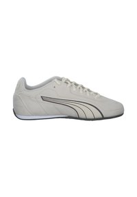 Beige ruskind sneakers med sorte accenter. Har en lav profil, rund tå og flad gummisål. Snørelukning og polstret krave.