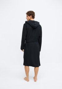 Robe de banho preta com capuz, feita de material macio, com cinto, mangas compridas e comprimento abaixo do joelho, com design simples.