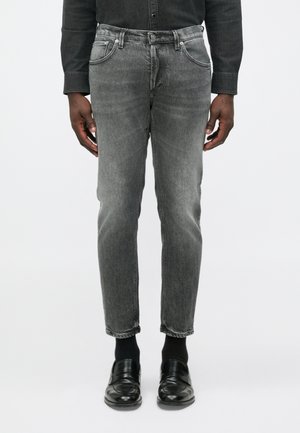 Grijze denim spijkerbroeken met een slanke pasvorm, vijfzakkenontwerp, vervaagde textuur en subtiele highlights, gecombineerd met zwarte instapschoenen en sokken.