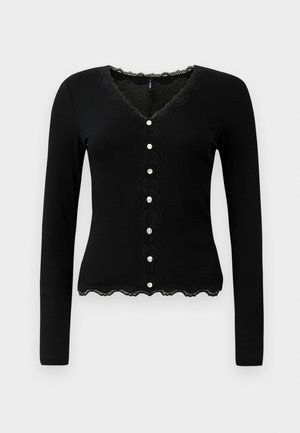 Mustat pitkät hihat kardigan, jossa on V-pääntie, pitsireunus ja koristeellinen nappilukko. Sisältää ribbikuvion ja aallotetun alahein.