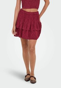 Bordeaux gekleurde gelaagde rok van zachte stof met een gerimpelde zoom. Heeft een elastische tailleband en een subtiele bloemenprint. Draag het met studded flats.