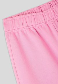 Tessuto in cotone rosa chiaro con una vita elasticizzata, caratterizzato da una texture arricciata nella parte superiore e una finitura liscia in tutto il resto.