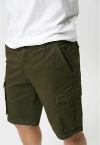 Shorts cargo de culoare verde măslinie, cu o textură netedă, având mai multe buzunare și un detaliu brodat cu logo pe față.