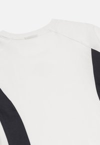 Katoenen T-shirt met een witte body en donkerblauwe zijpanelen, ronde hals en licht gestructureerde stof voor een casual uitstraling.