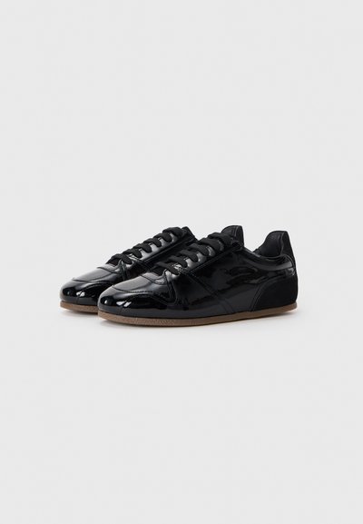 Black patent leather sneakers with a smooth finish, round toe, black laces, and a gum rubber sole. Subtle design detailing on the sides.