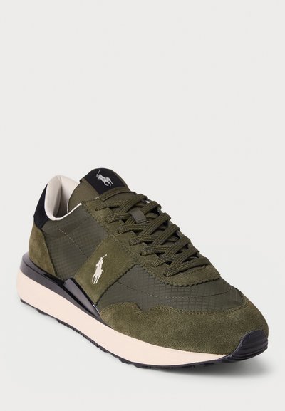 Green sneaker featuring a mix of textured suede and smooth nylon materials, a black heel accent, and a white midsole. Logo detail on the side.