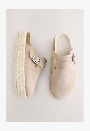 Bézs színű, velúr anyagú papucs espadrilles talppal, ezüst csattal, puha tapintású, könnyen felhúzható kivitelben.