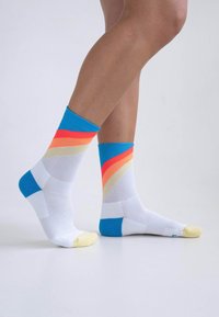 Bunte Knöchelsocken in Weiß mit blauen, orangenen und gelben diagonalen Streifen; aus leichtem, atmungsaktivem Stoff mit strukturierten Akzenten gefertigt.