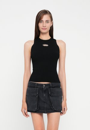 Black ribbed tank top with high neckline and silver logo accent, paired with a dark denim skirt featuring front pockets.
