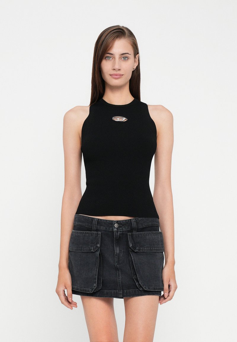Svart ribbet singlet med høy hals og sølvlogo, kombinert med en mørk denimskjørt med frontlommer.