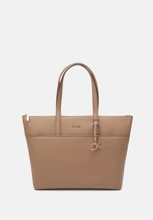 Braune Leder-Umhängetasche mit zwei Griffen, glatter Oberfläche, Reißverschluss und Logo-Detail in goldfarbener Ausführung. Mit einem kleinen Charm versehen.