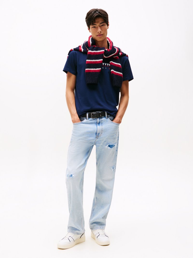 Marineblaues T-Shirt mit Logo, hellblaue abgewetterte Jeans, rot-navy gestreifter Schal, weiße Sneakers, lässiger Schnitt, minimalistisches Design.