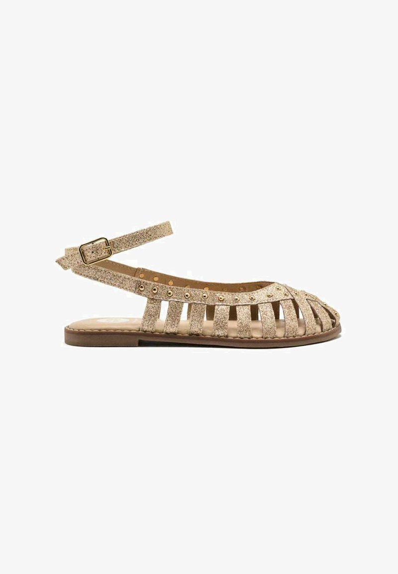 Sandalias slingback de purpurina dorada con diseño de punta abierta, que presentan múltiples recortes y tachuelas redondas a lo largo de la correa. Suela plana.
