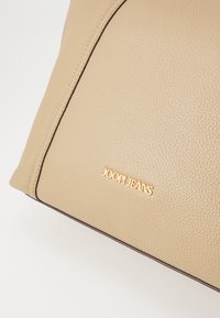 Bež usnjena torbica z teksturirano površino, kontrastnimi temnimi šivi in z zlatim logotipom "JOOP.JEANS" spredaj.