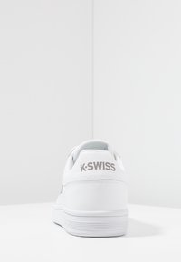 Sneakers K-Swiss bianchi con tomaia in pelle liscia, forma arrotondata e suola testurizzata, con logo argentato sulla linguetta del tallone.