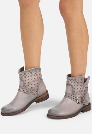 Botas de tobillo de cuero gris que presentan una parte superior perforada con una correa decorativa y hebilla, punta redonda y un tacón de madera bajo y apilado.