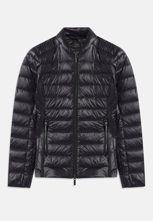 Melnas spīdīgas, quiltētas pūkaino jaku ar augstu apkakli, priekšējo rāvējslēdzēju un divām ar rāvējslēdzējiem kabatām, izvietota uz baltas fona.