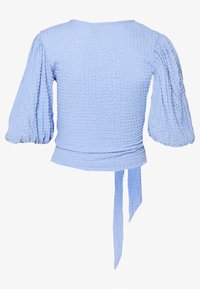 Ljusblå kort topp med strukturerad, krinklad tyg och puffärmar; har ett midjeband baktill för justerad passform.