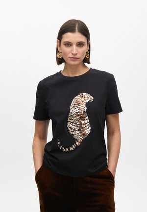 Camiseta negra de manga corta con un diseño de tigre en lentejuelas en tonos dorados y bronces, con un corte relajado y cuello redondo.