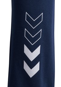 Marineblauwe sportbroek met een gestructureerd oppervlak, voorzien van een verticale witte chevronprint aan de zijkant voor een extra detail.