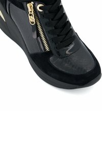 Mustat high-top-tennarit, joissa on yhdistelmä kiiltävää lakkaa ja teksturoituja materiaaleja. Varustettu kultaisella vetskalla ja mustilla nauhoilla.