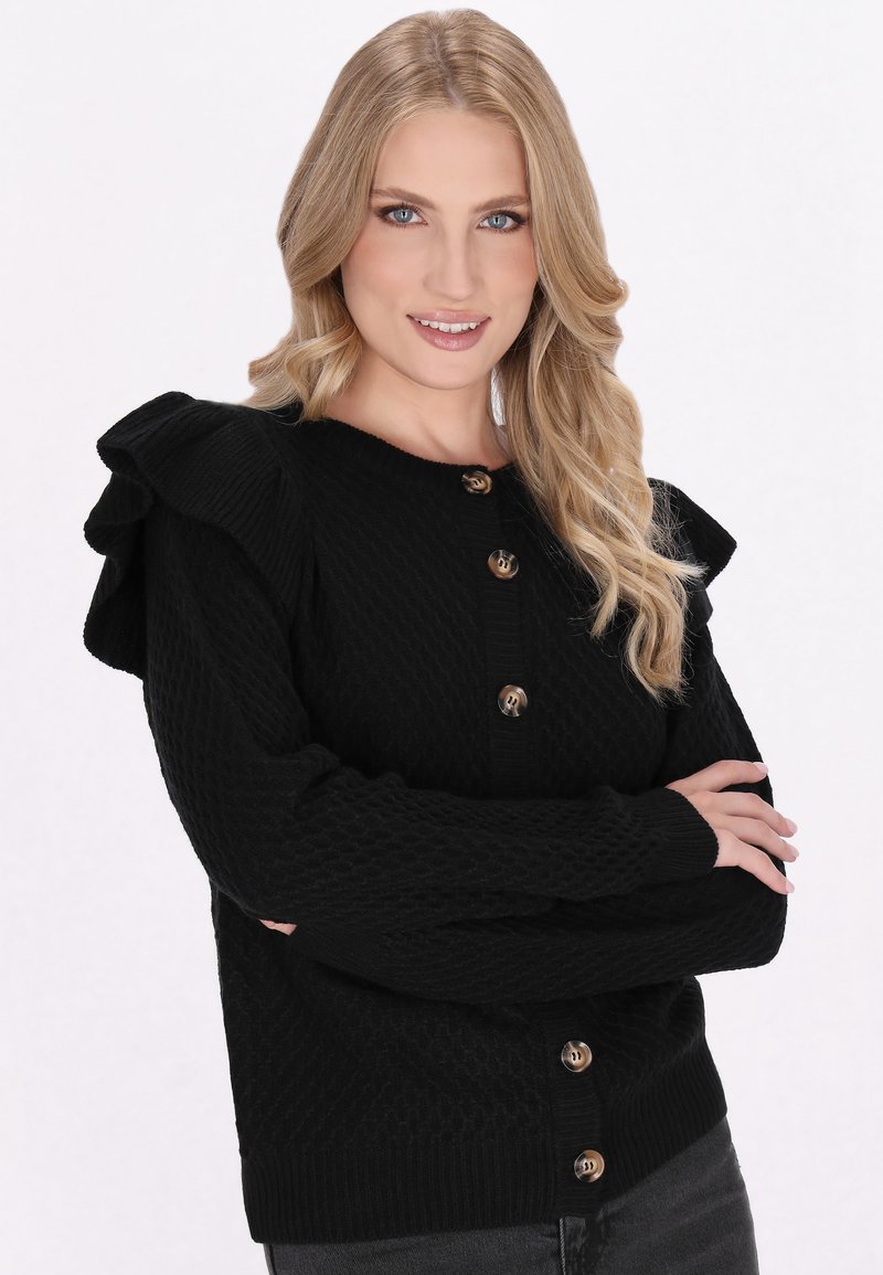 Zwarte gebreide cardigan met een gestructureerd patroon, ruches op de schouders en een ronde halslijn. Voorzien van gouden knopen in het midden.