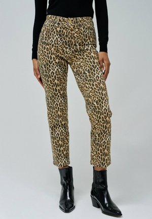 Pantalones de estampado de leopardo con un diseño ajustado, en colores beige y negro, con una cintura de altura media y bolsillos laterales, combinados con botas negras de tobillo.