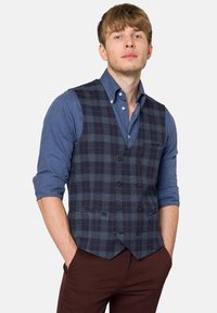 Granatowa kamizelka w kratkę z kontrastującymi szarymi i bordowymi wzorami, wyposażona w cztery guziki i kieszenie, noszona na niebieskiej koszuli z guzikami.