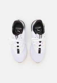 Des baskets de sport blanches avec une tige en maille, des semelles texturées, des accents noirs et un design à lacets. Étiquette "SoftRide" sur la languette.