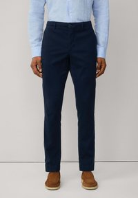 Navy blue chinos made from cotton, featuring a straight fit, zip fly, and button closure. Smooth texture with side pockets and belt loops.