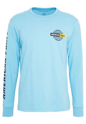 Chemise bleu clair à manches longues avec le texte "American Eagle" et le logo globe sur la poitrine, et "American Eagle" imprimé verticalement sur la manche gauche.