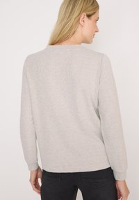 Pull gris à manches longues, texture douce, poignets côtelés et col rond. Le dos présente un design minimaliste.